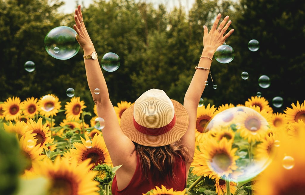 a woman in a hat and sunflowers in a field