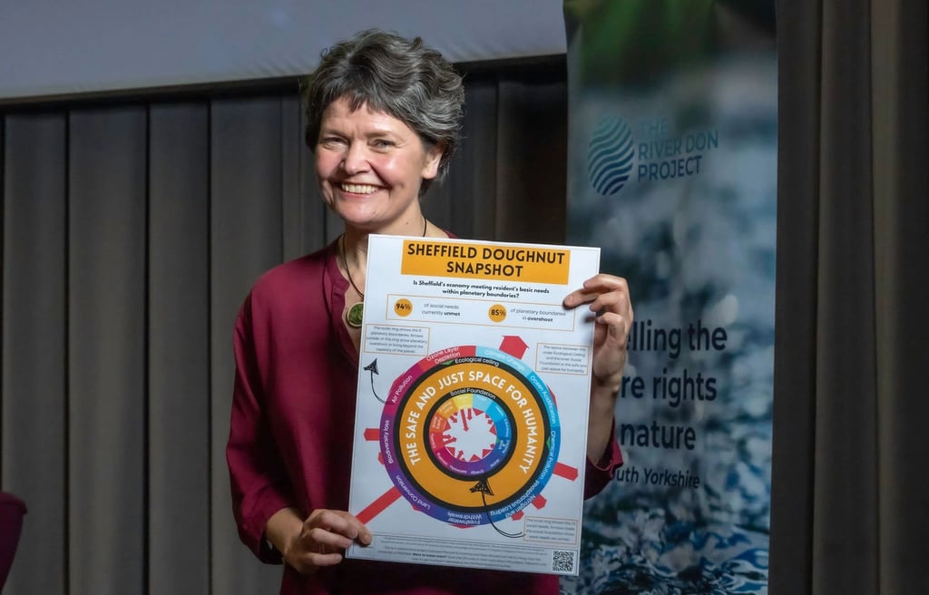 Photograph of Kate Raworth, creator of Doughnut Economics holding up a poster of the Sheffield Dough
