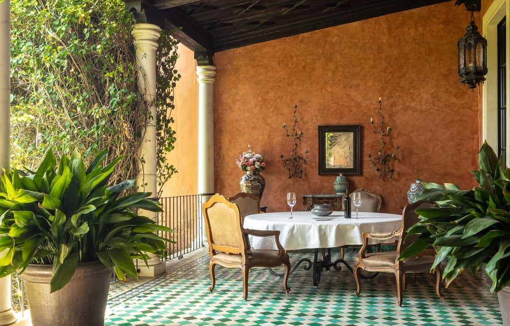 Covered terrace dining area with green mosaic floor and terracotta walls