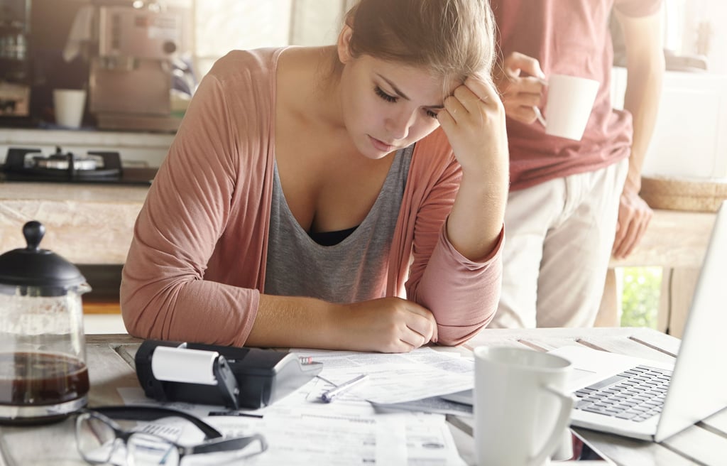 Young casual female having depressed look while managing family finances and doing paperwork