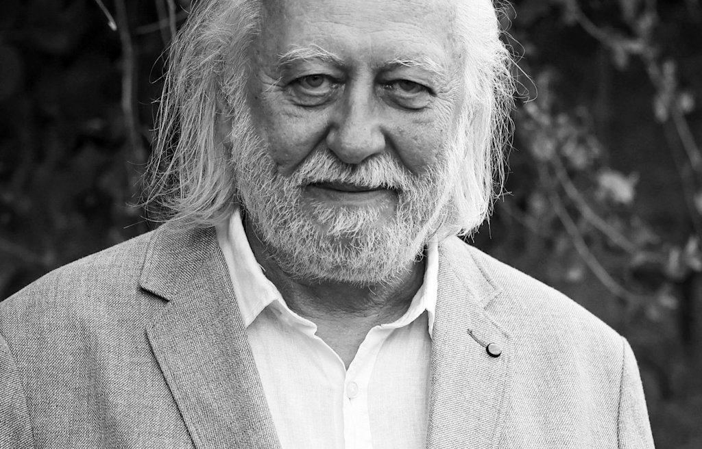 Black and white portrait of an elderly man in a blazer, possibly László Krasznahorkai, with his face