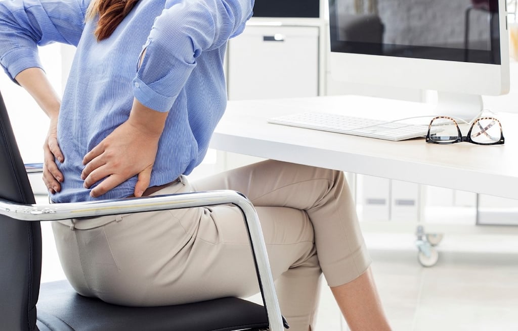 Young woman holding her back, in pain.