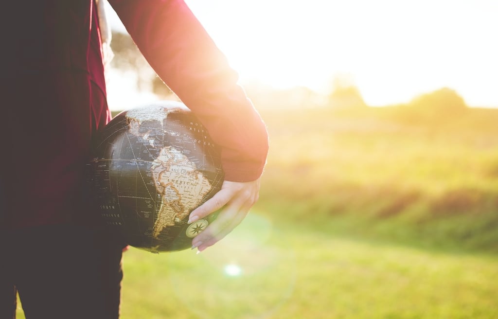 Young person holding a globe in their hand.