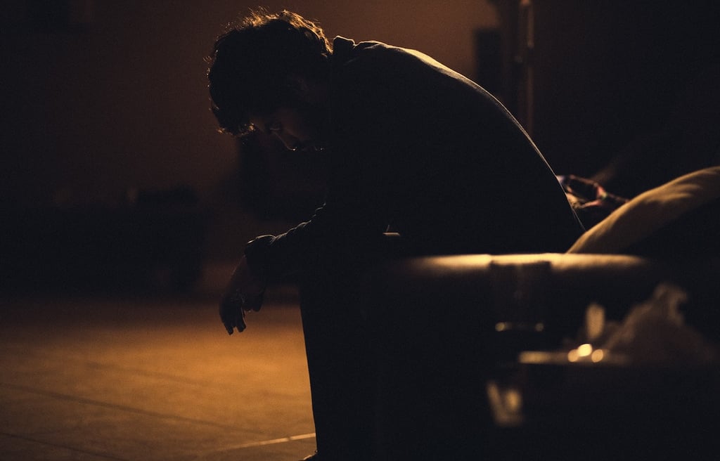 Man sitting alone on a bench at night, signifying depression and pain.