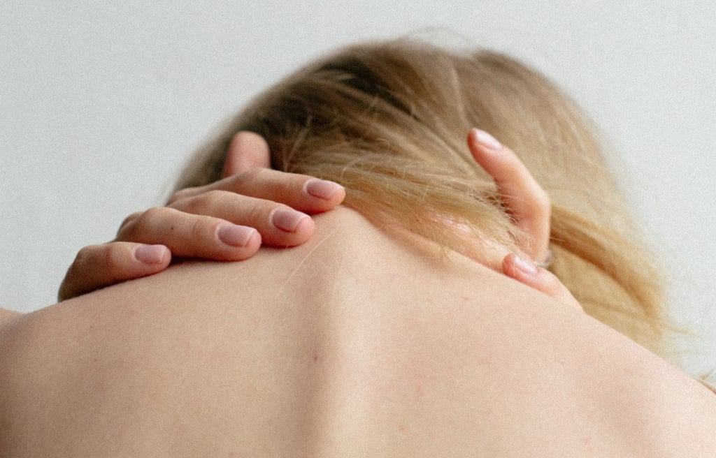 Young woman holding the back of her neck, demonstrating musculoskeletal pain.