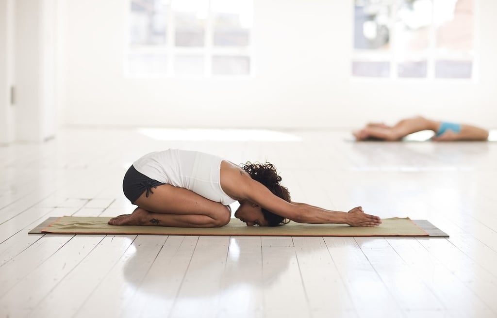 Young woman practising yoga on a mat indoors.