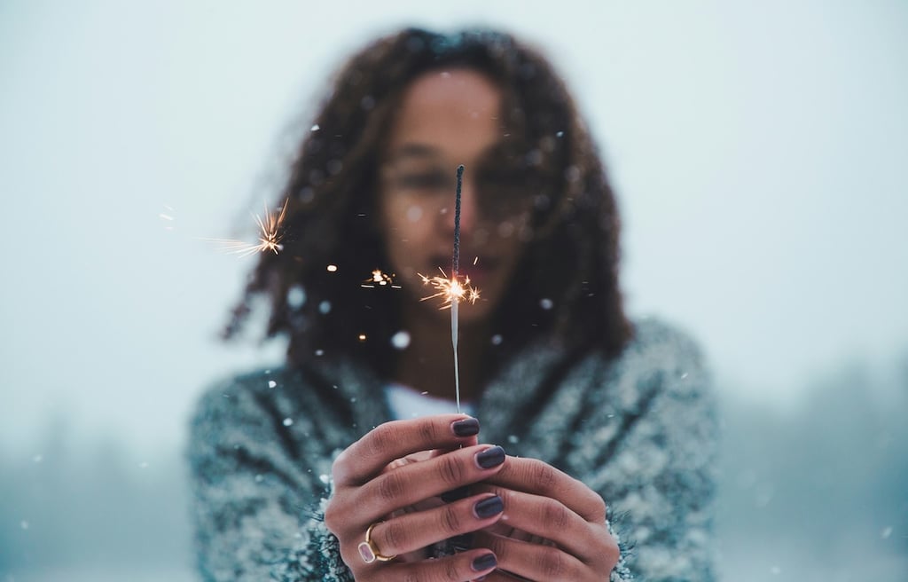 Young woman holding a fire cracker in the cold winter.