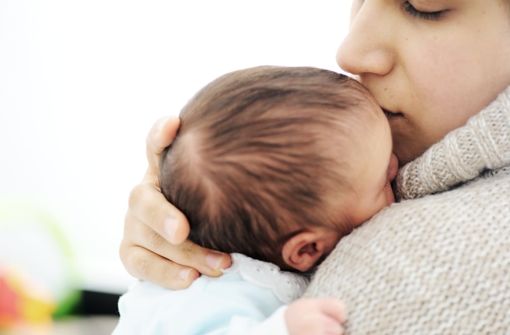 A woman is kissing her baby on the head