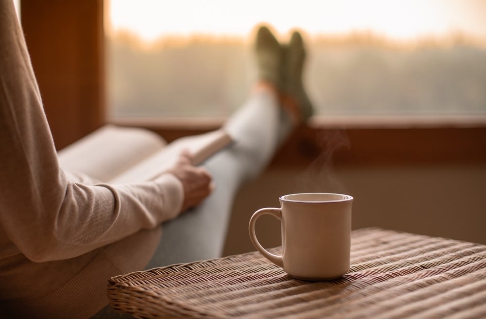 A person sitting on a chair with a cup of coffee, relaxing