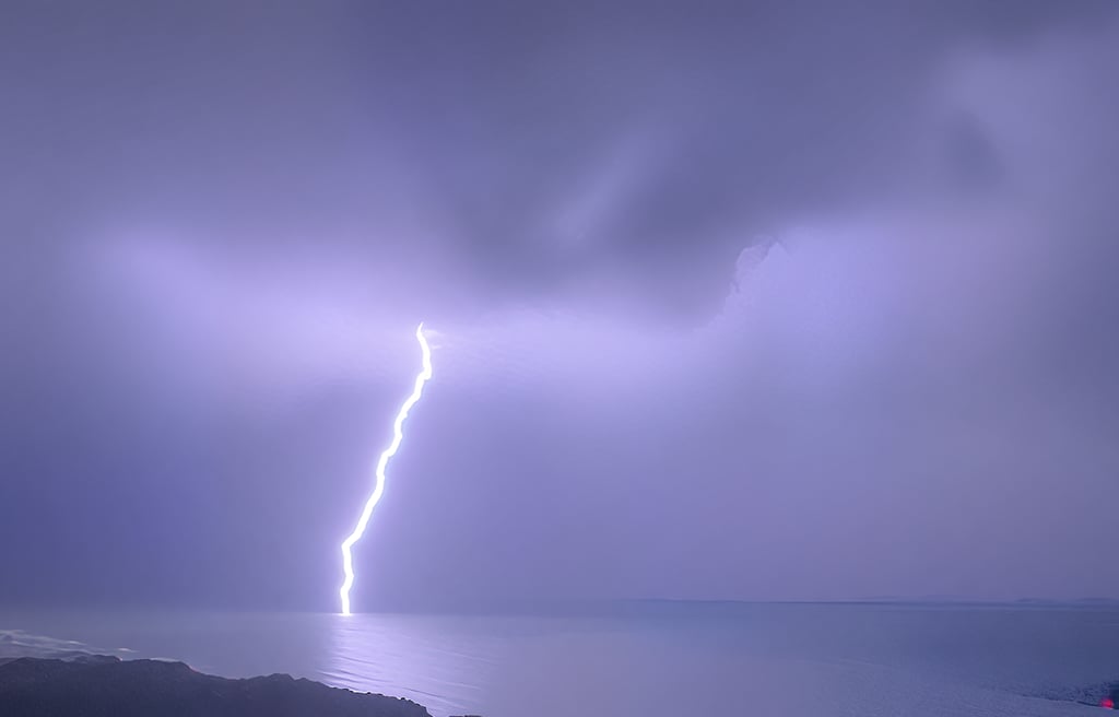 Powerful lightning strike over ocean at dusk, severe weather warning for wilderness survival and outdoor safety