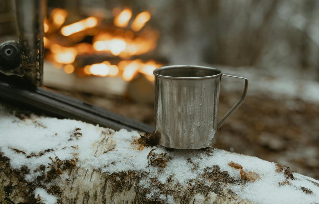 Metal mug and stick by snowy campfire, demonstrating off-grid outdoor cooking