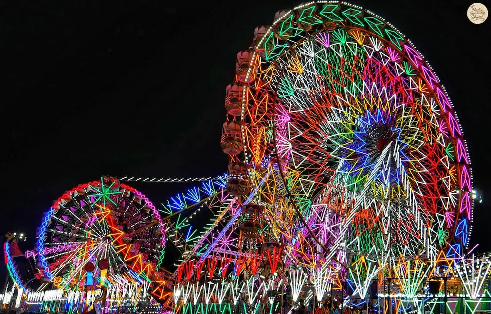 Amusement rides glowing with colorful carnival lights at Kota Dussehra Mela night view.