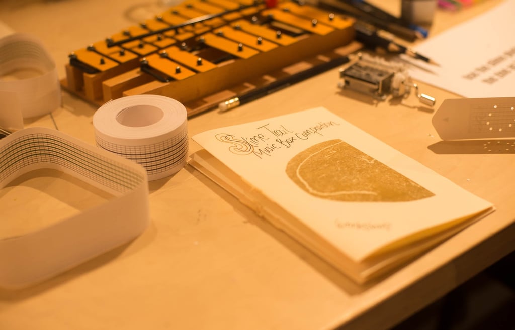 a table with a glockenspiel and a zine about music box composition