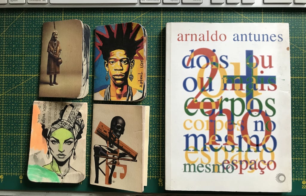 Caderno de artista com anotações e desenhos. Ao lado livro Arnaldo Antunes.