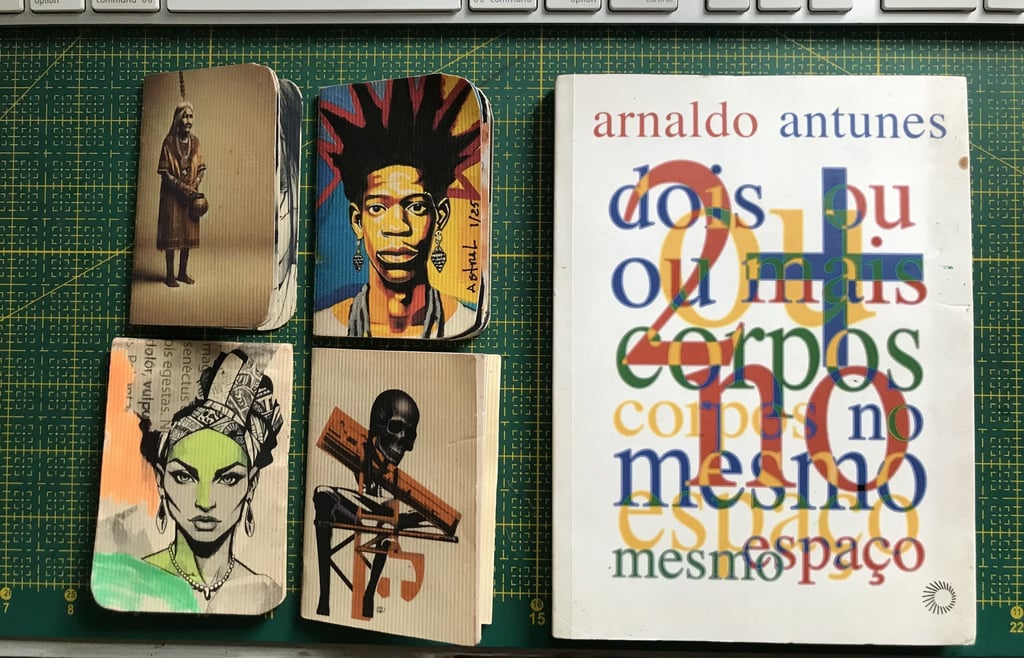 Caderno de artista com anotações e desenhos. Ao lado livro Arnaldo Antunes.