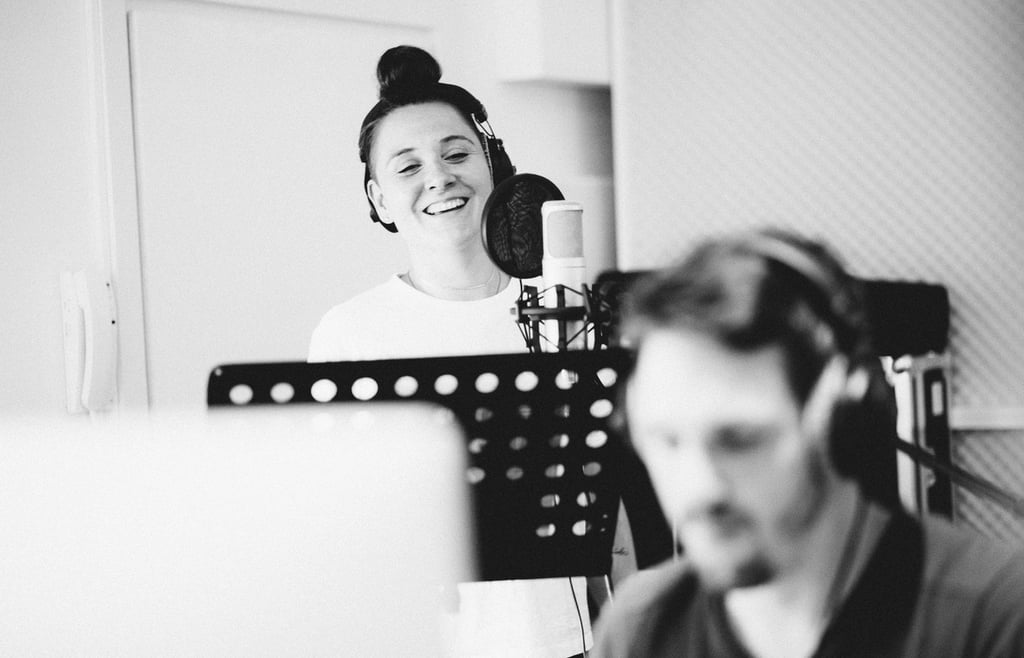 Female vocalist recording in studio booth during vocal session