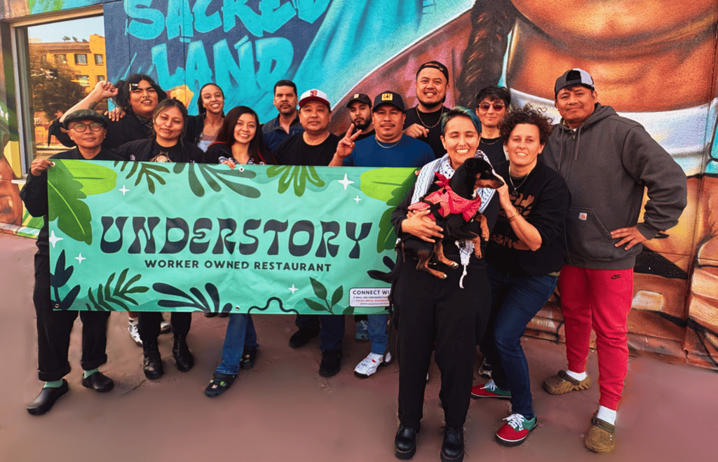 Understory workers standing in front of a mural of a man holding a banner