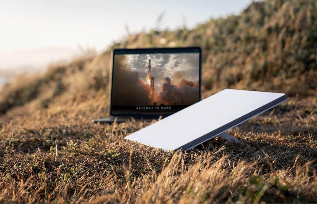 Portable Starlink satellite dish and laptop with high-speed internet in a remote outdoor field.