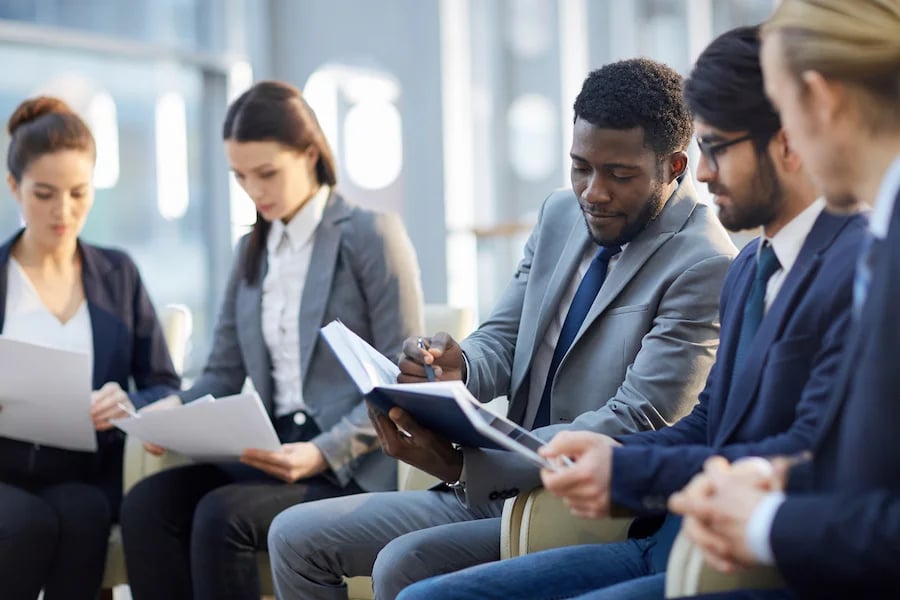 imagem mostra um grupo de executivos em uma reunião compostas de homens e mulheres lado a lado.