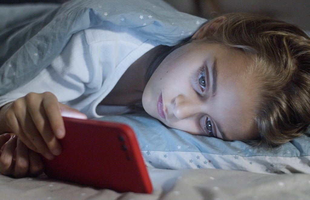 a child is laying on a bed with a red phone