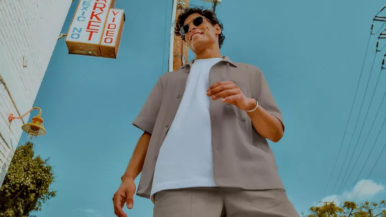 A man wearing an outfit from lululemon: beige collared shirt, white t-shirt, and beige shorts.