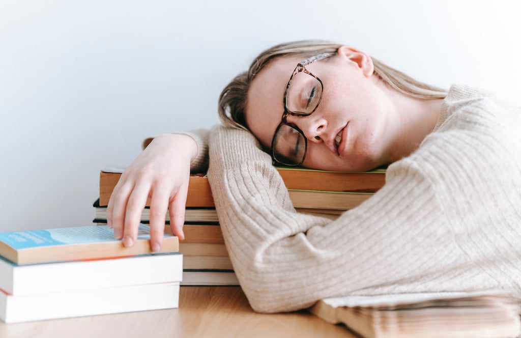 a woman is sleeping on a stack of books fatigue due to vitamin b12