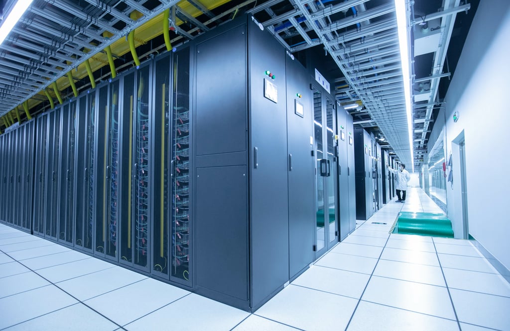 A technician inspects rows of black server racks in a modern data centre.