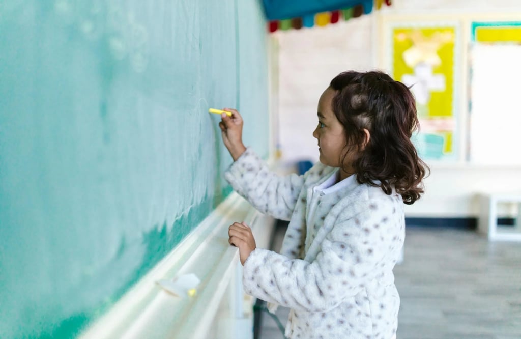 A girl writes on a chalkboard.