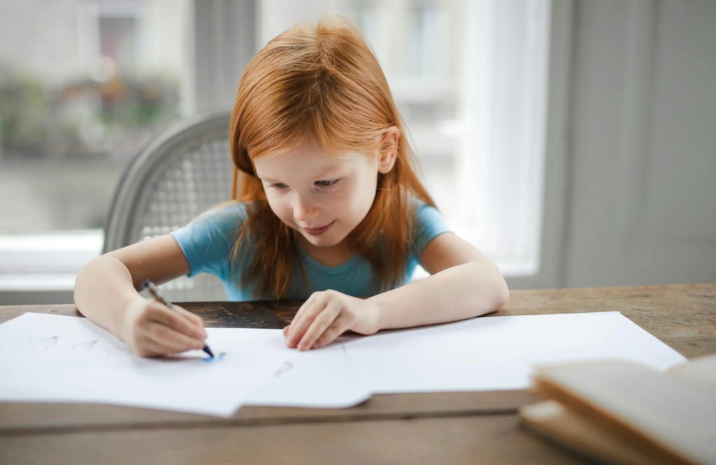 A little girl draws and writes at home.