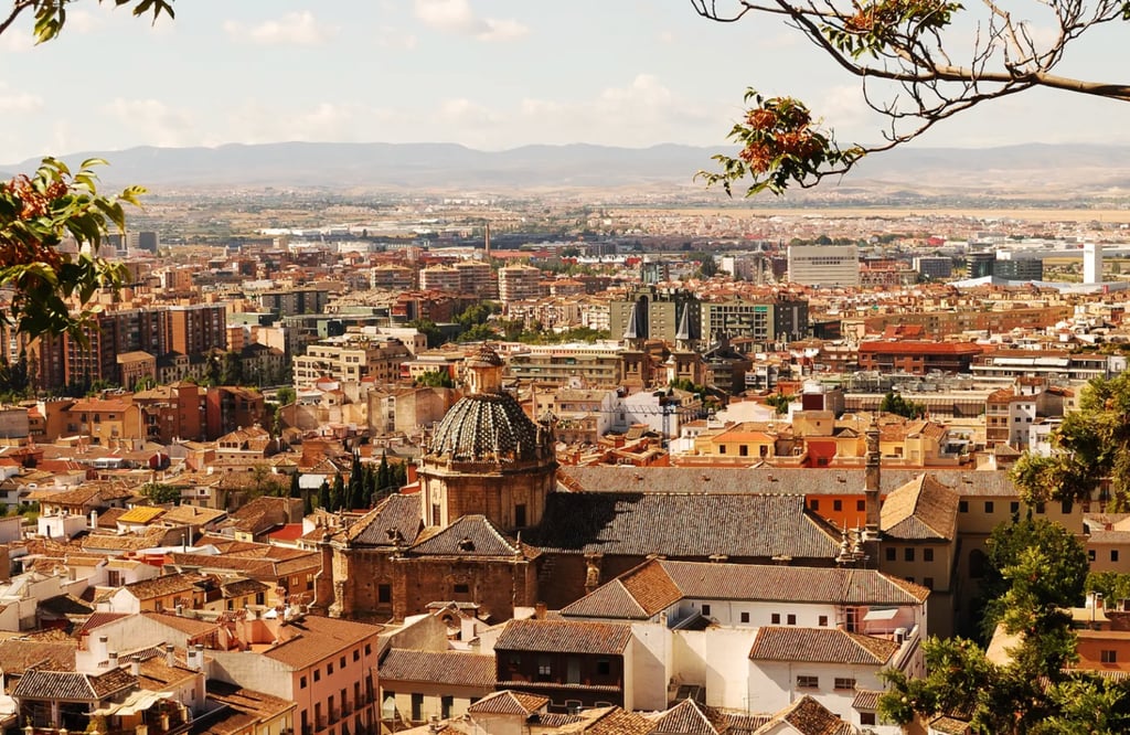 Panoramic cityscape view of Granada, Spain featuring historic tiled roofs and the domed Parroquia del Sagrario.