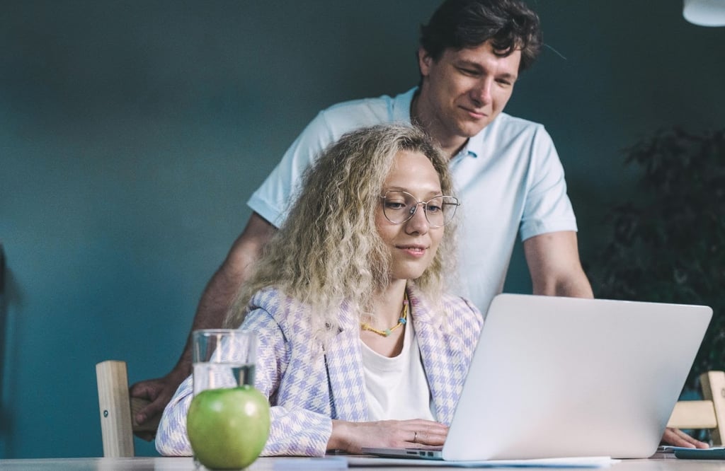 a man and woman sitting at a table with a laptop
