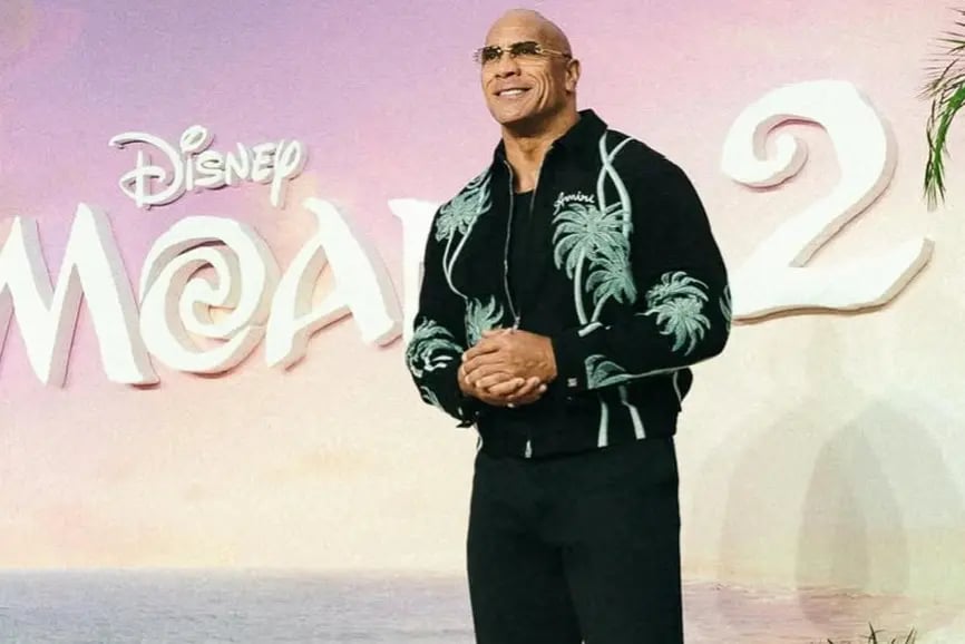 a man in a black shirt and sunglasses standing in front of a sign that says