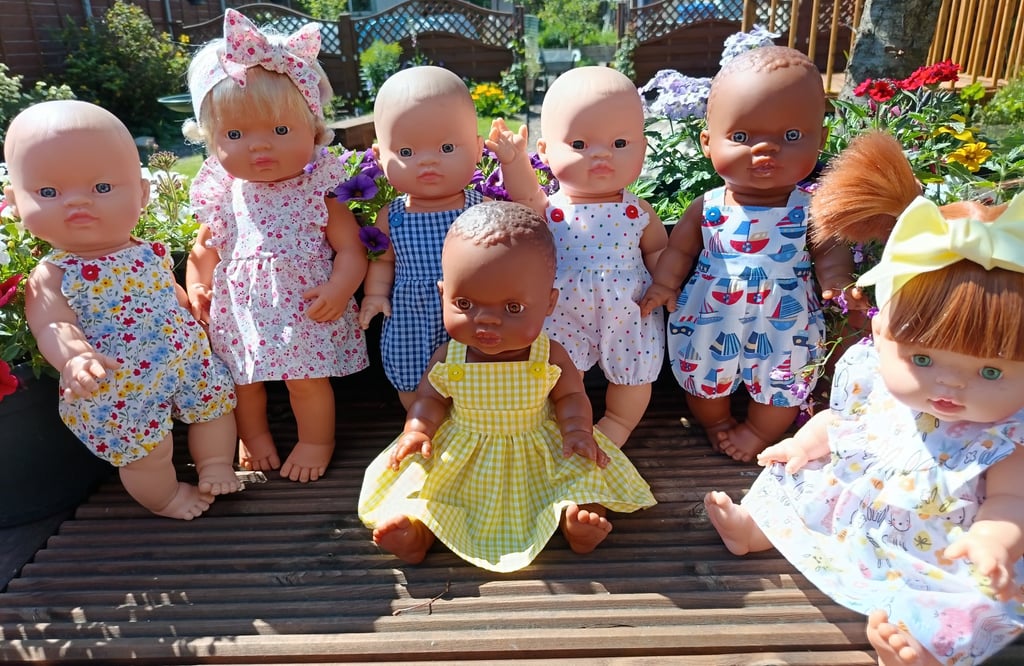 A group of Minikane dolls sitting on a wooden deck