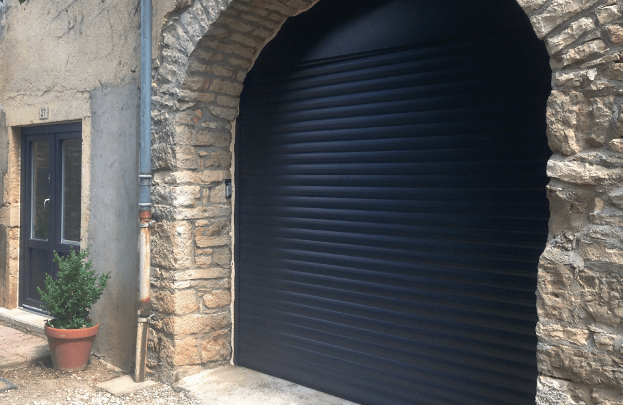 Porte de garage enroulante gris anthracite RAL 7016 installée sur façade en pierre par LB Menuiserie