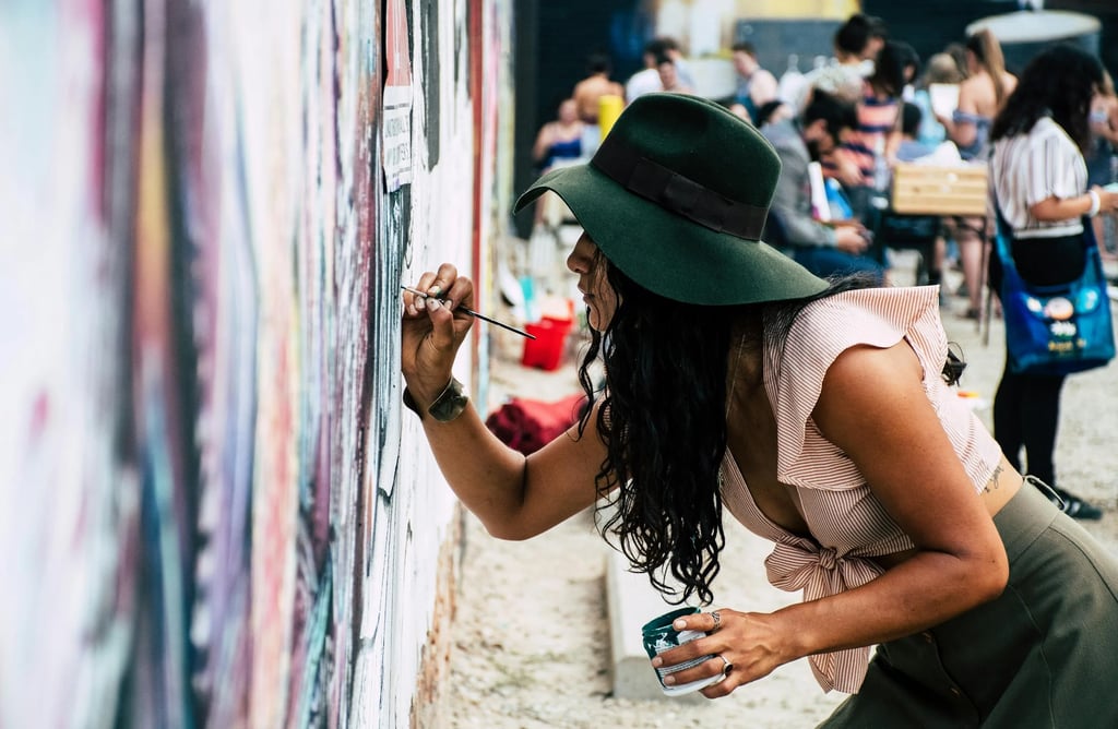Um coletivo de mulheres, criando um mural de arte urbana.