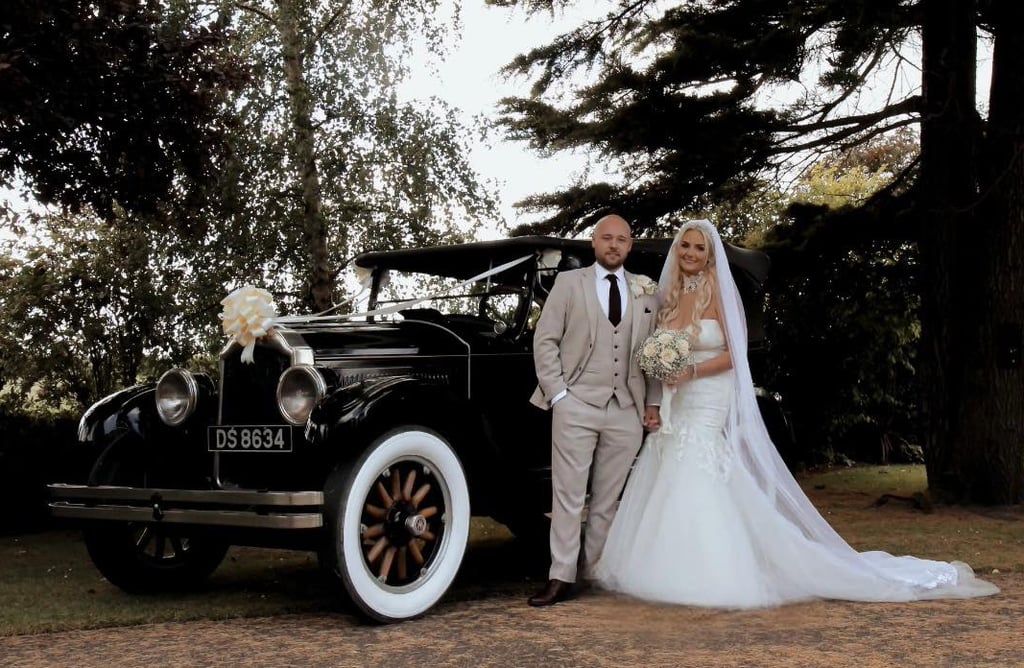 Wedding couple standin by posh car