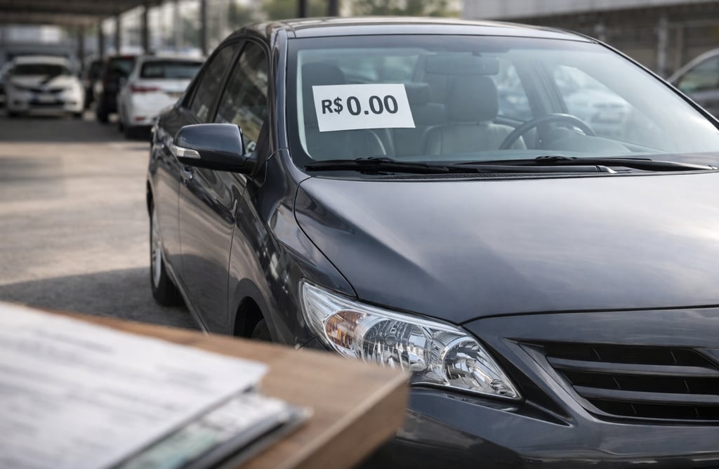 Sedã usado bem conservado em pátio de concessionária com etiqueta de preço no para-brisa