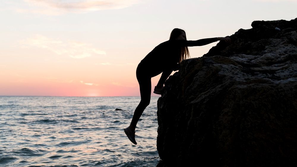 a woman standing on a rock in the ocean
