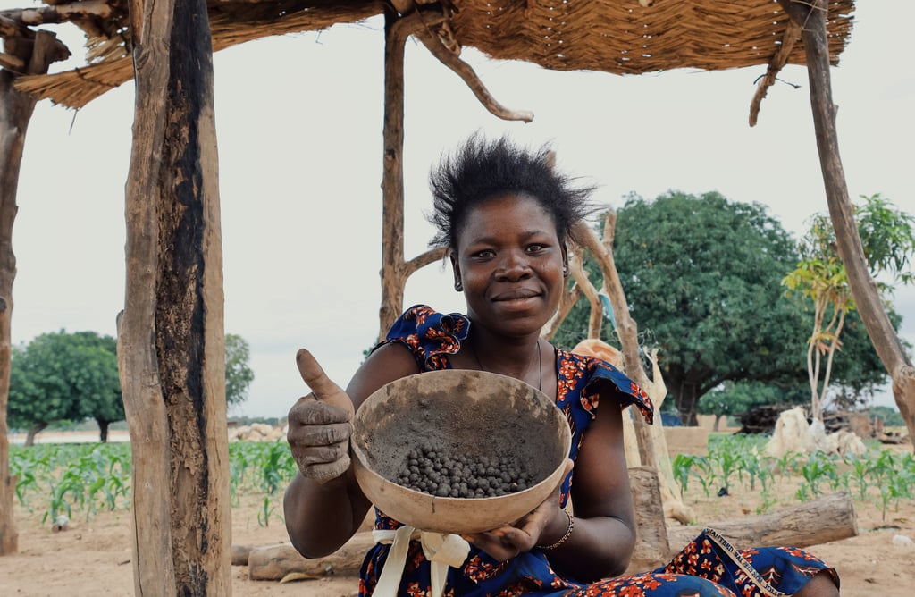 A young african lady holding a calabash full of seeds