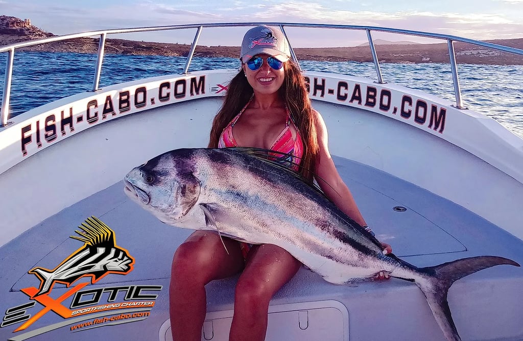 a woman in a bikini top and sunglasses holding a fish