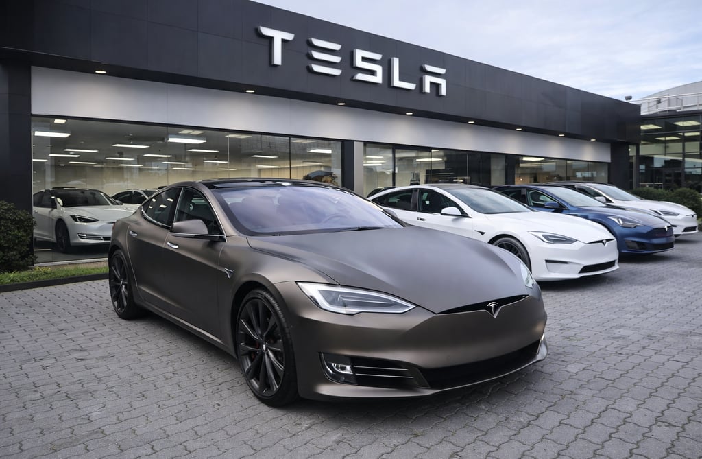 Tesla Model S estacionado em frente a concessionária Tesla com outros modelos ao fundo