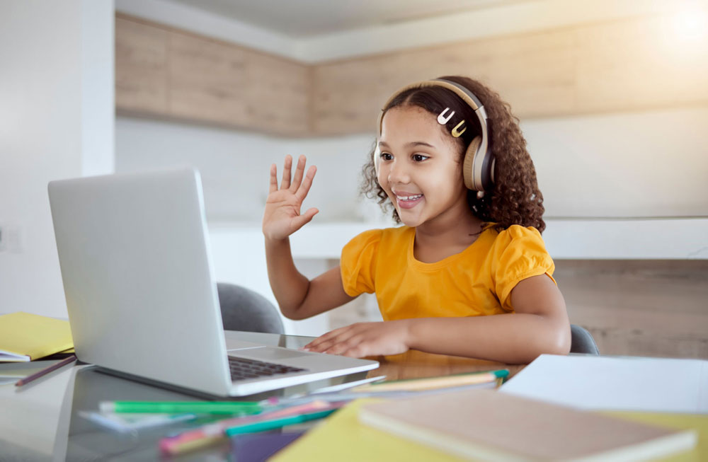a young girl with headphones and a laptop waving hand