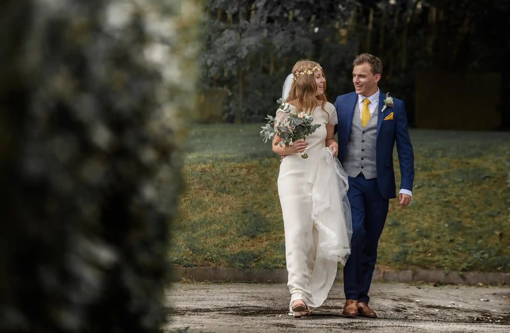 A smiling bride and groom walking together outdoors after their wedding ceremony.
