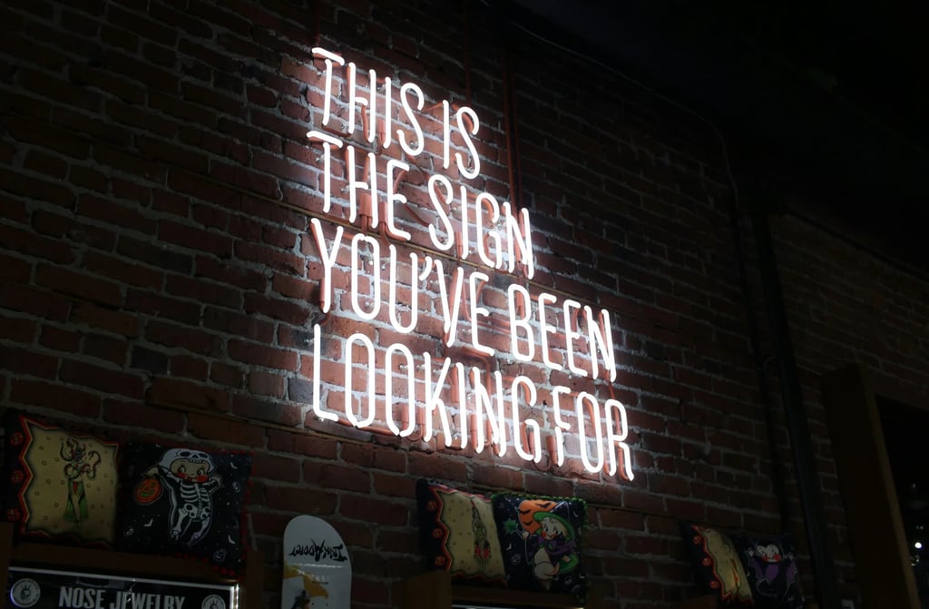 A neon sign on a wall with the text, this is the sign you have been looking for