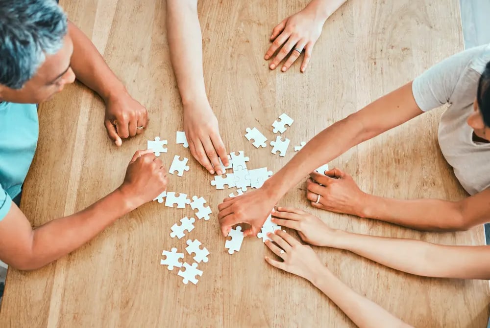 3 people solving a puzzle on a table