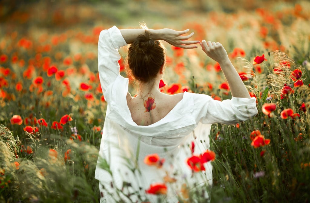a woman in a white dress standing in a field of flowers