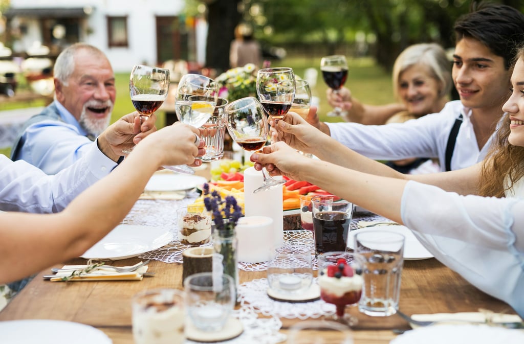 Multi-generational family toasting with wine glasses at a festive outdoor garden dinner party.