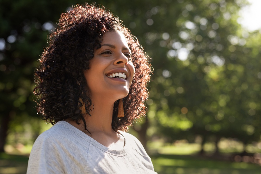 A woman smiling and looking up and enjoying life with peace, happiness and contentment