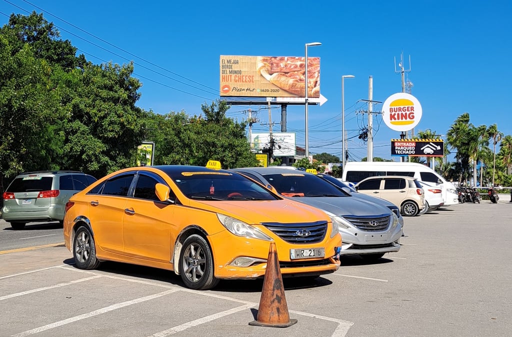 Taxi service in Dominican Republic with yellow car parked near restaurants and shops