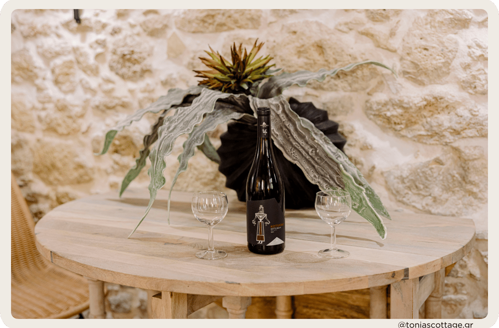 Table at Tonia's Cottage with a bottle of Lyrarakis wine and two glasses, set for a relaxing moment